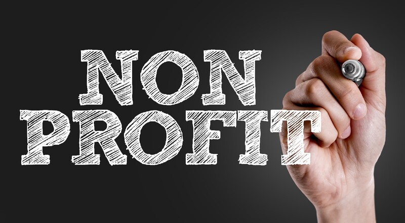 A hand holds a marker or chalk after having written the word "Nonprofit." Stock Photo