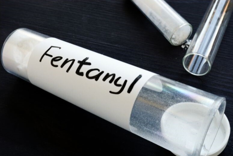 A white medical test tube is labelled "Fentanyl," on a black background. Stock Photo.