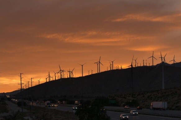 The mountains topped by windmills are dark and underneath a dramatic sky. Stock Photo